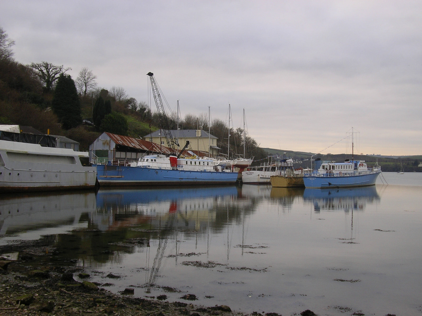 Boats moored at a quiet boatyard in the off-season under overcast winter skies